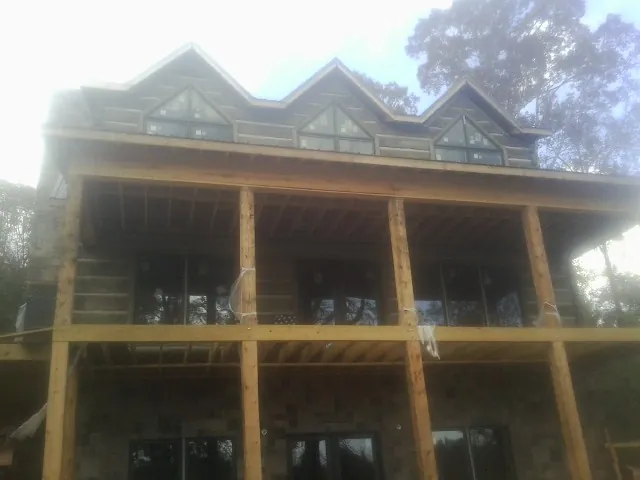 Dormers and porch framing on a large log home under construction — Roof Coating work by our crew in Howells