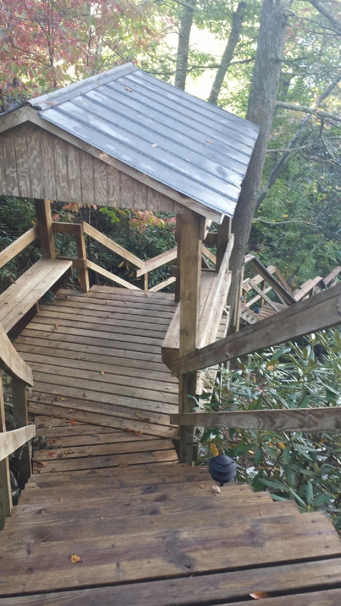 Metal roofed shelter over wooden steps on a wooded walkway — Skylight Repair & Installation work by our crew in Howells
